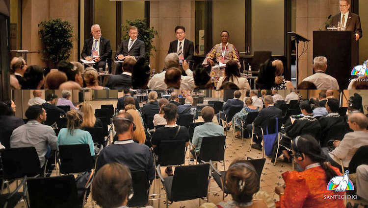 Photo: Chair (on podium), four panelists and a section of the audience of the Forum on 